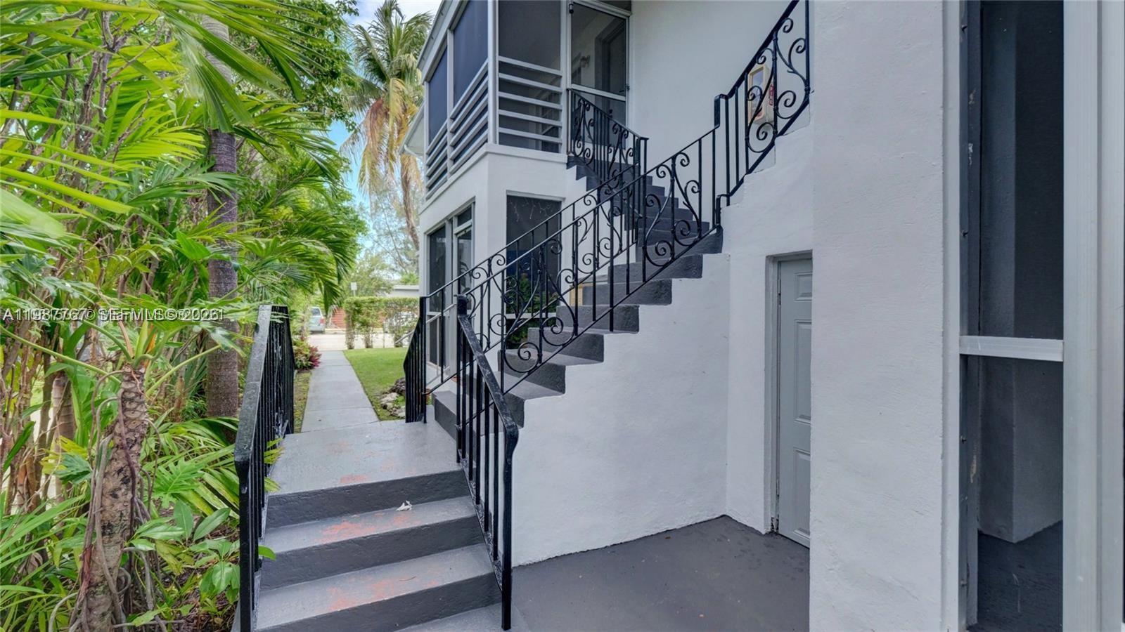 An exterior view of a white building with an outdoor staircase and metal railings — 1791 Marseille Dr, Miami Beach FL 33141, MIAMI BEACH, FL
