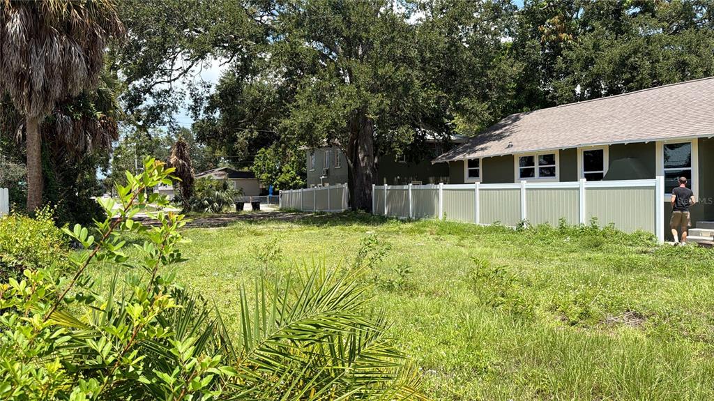 A grassy vacant lot sits next to a house with a white vinyl fence — 1145 NEWTON AVENUE S, ST PETERSBURG, FL