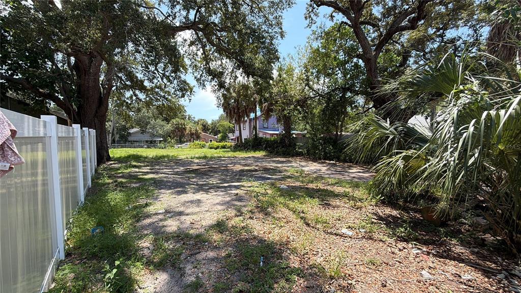 A vacant, partially shaded lot features a white vinyl fence on the left side — 1145 NEWTON AVENUE S, ST PETERSBURG, FL