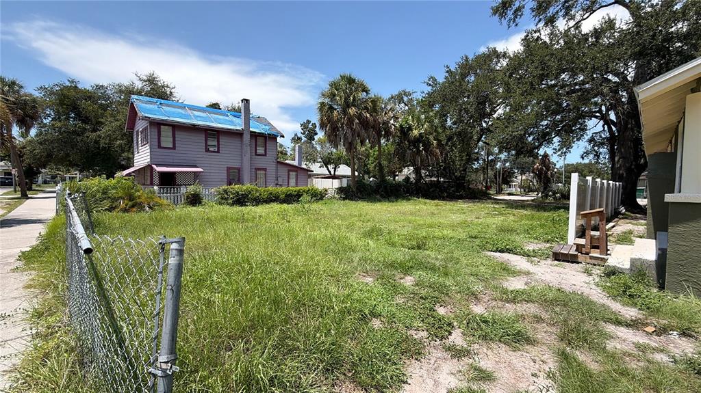 A vacant, grassy lot sits next to a two-story house with a blue tarp roof — 1145 NEWTON AVENUE S, ST PETERSBURG, FL