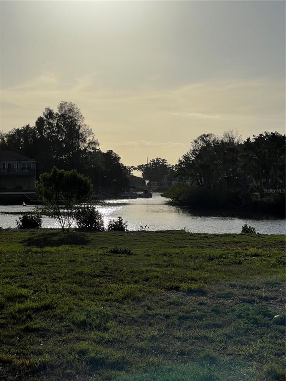 A grassy yard overlooks a narrow canal with trees and houses in the distance — 14539 OLD DIXIE HIGHWAY, HUDSON, FL
