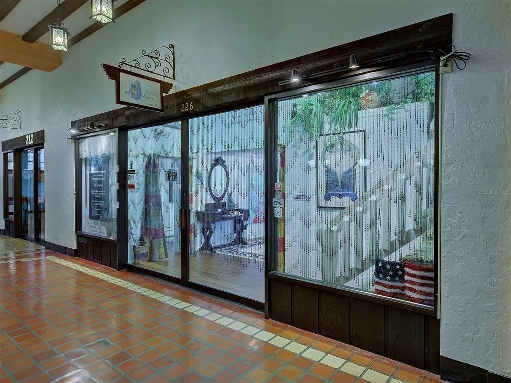 A storefront with glass doors, bead curtains, and a wooden frame in an indoor hallway — 226 TAMPA AVENUE W UNIT 18A, VENICE, FL