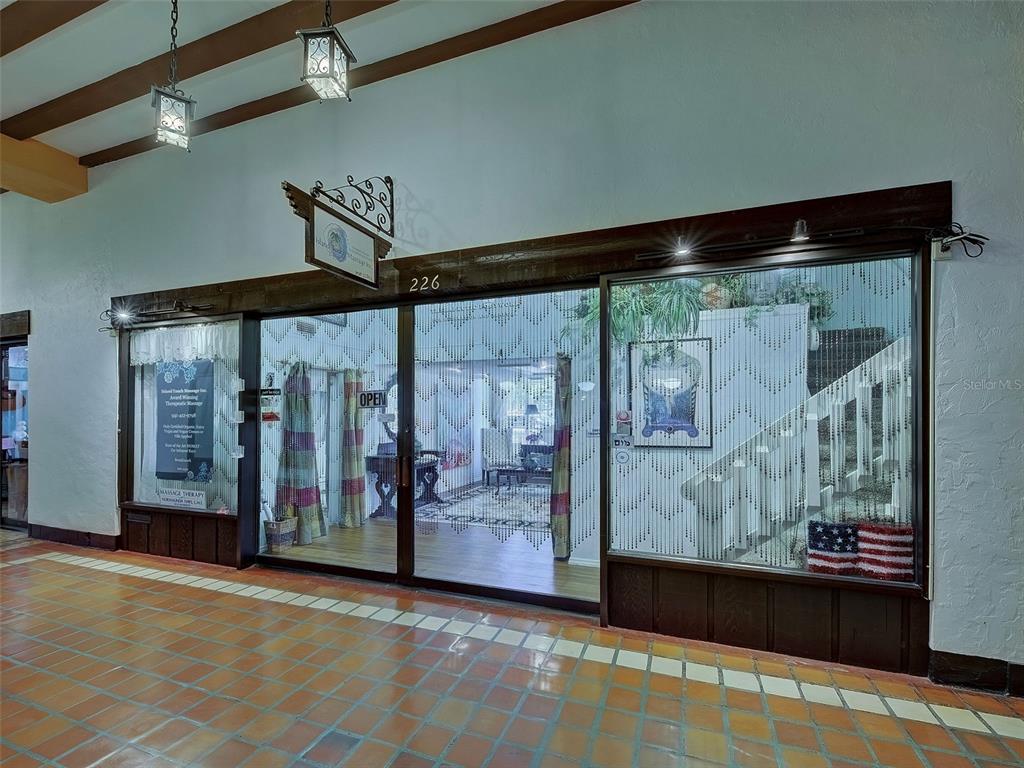 The exterior storefront of a business features glass doors, a wooden frame, and tiled flooring — 226 TAMPA AVENUE W UNIT 18A, VENICE, FL