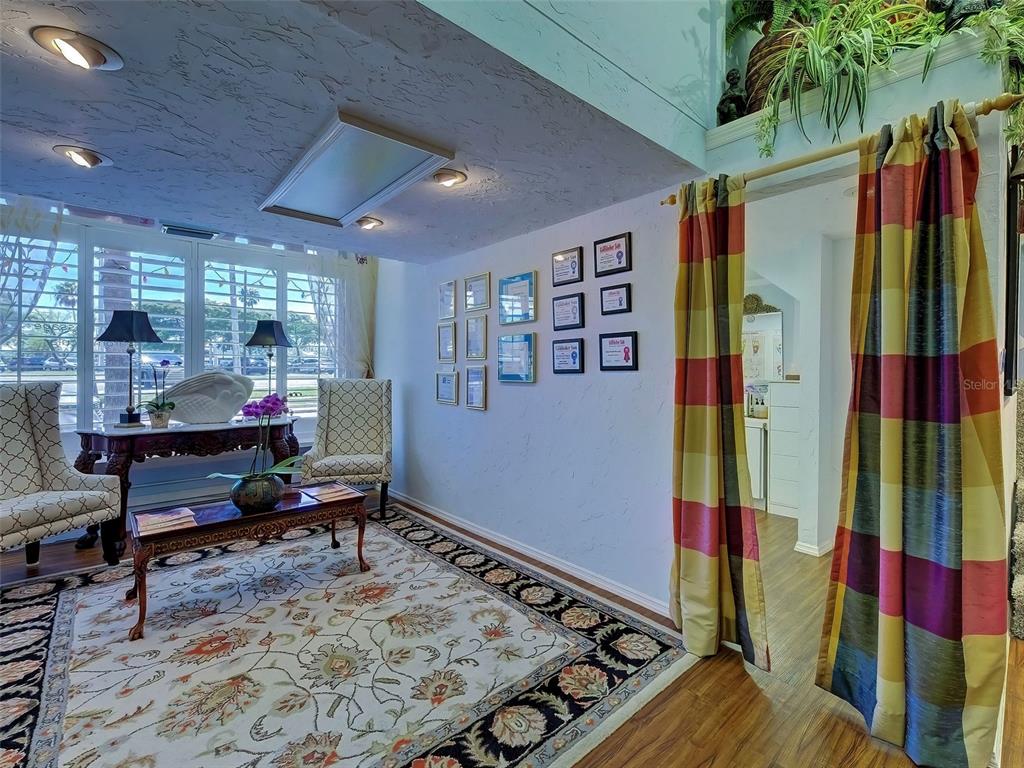 A living room features a patterned area rug, two armchairs, and a wall of framed certificates — 226 TAMPA AVENUE W UNIT 18A, VENICE, FL