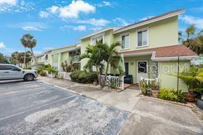 A light green two-story townhouse exterior with a parking area and palm trees — 3595 41ST LANE S UNIT H, ST PETERSBURG, FL
