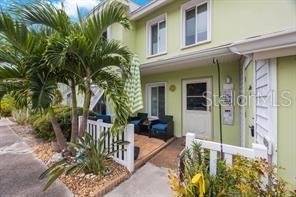A light green townhouse exterior features a small patio, white picket fence, and palm trees — 3595 41ST LANE S UNIT H, ST PETERSBURG, FL