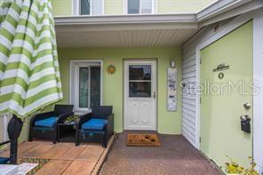 A covered patio features two chairs with blue cushions and a front door — 3595 41ST LANE S UNIT H, ST PETERSBURG, FL