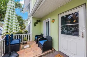 A covered porch features tiled flooring, two dark wicker chairs, and a white entry door — 3595 41ST LANE S UNIT H, ST PETERSBURG, FL