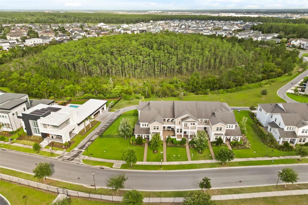 An aerial view shows a multi-unit residential building with a large forest in the background — 14229 KELLOGG AVENUE, ORLANDO, FL