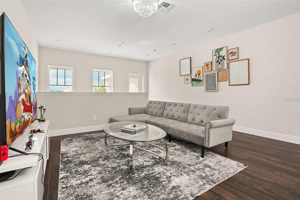A living room features a grey tufted sofa, glass coffee table, and a wall gallery — 14229 KELLOGG AVENUE, ORLANDO, FL