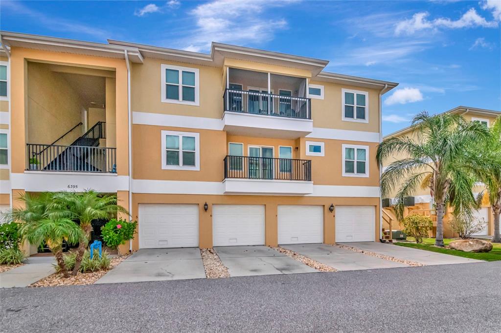 A three-story apartment building features four ground-level garages and two levels of balconies — 6395 BANYAN BOULEVARD UNIT 303, NEW PORT RICHEY, FL