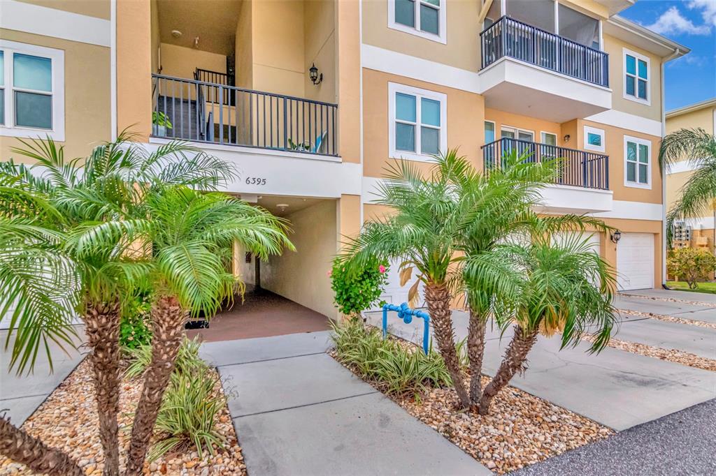 A multi-story apartment building exterior features palm trees, a covered entryway, and balconies — 6395 BANYAN BOULEVARD UNIT 303, NEW PORT RICHEY, FL