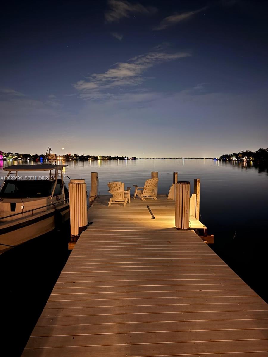 A wooden dock with two chairs extends into a calm body of water at night — 8300 Hawthorne Ave, Miami Beach FL 33141, MIAMI BEACH, FL
