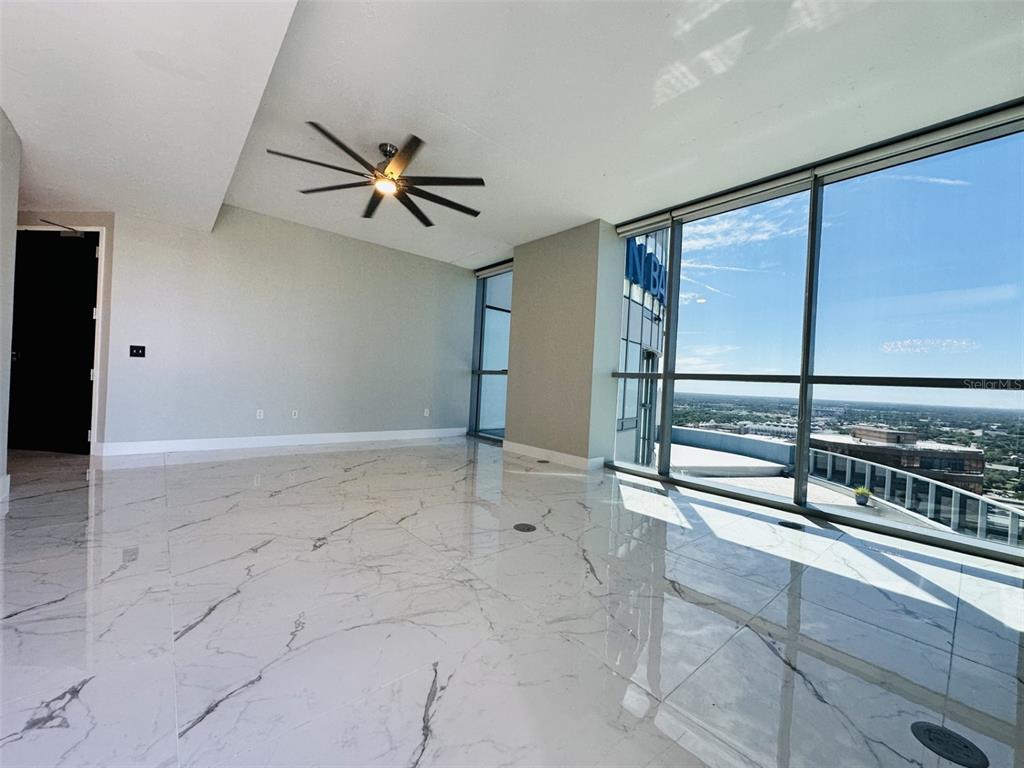A modern room features white marble tile flooring, a ceiling fan, and floor-to-ceiling windows — 111-3 WASHINGTON STREET, ORLANDO, FL