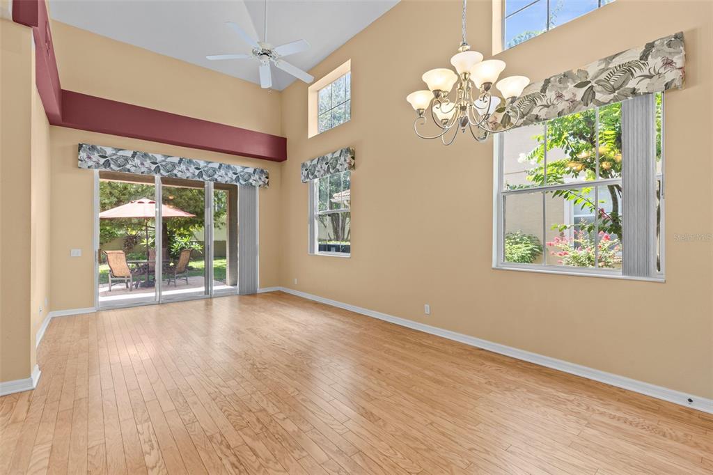 A bright dining room with hardwood floors, a vaulted ceiling, and a large chandelier — 3350 COVERED BRIDGE DRIVE W, DUNEDIN, FL