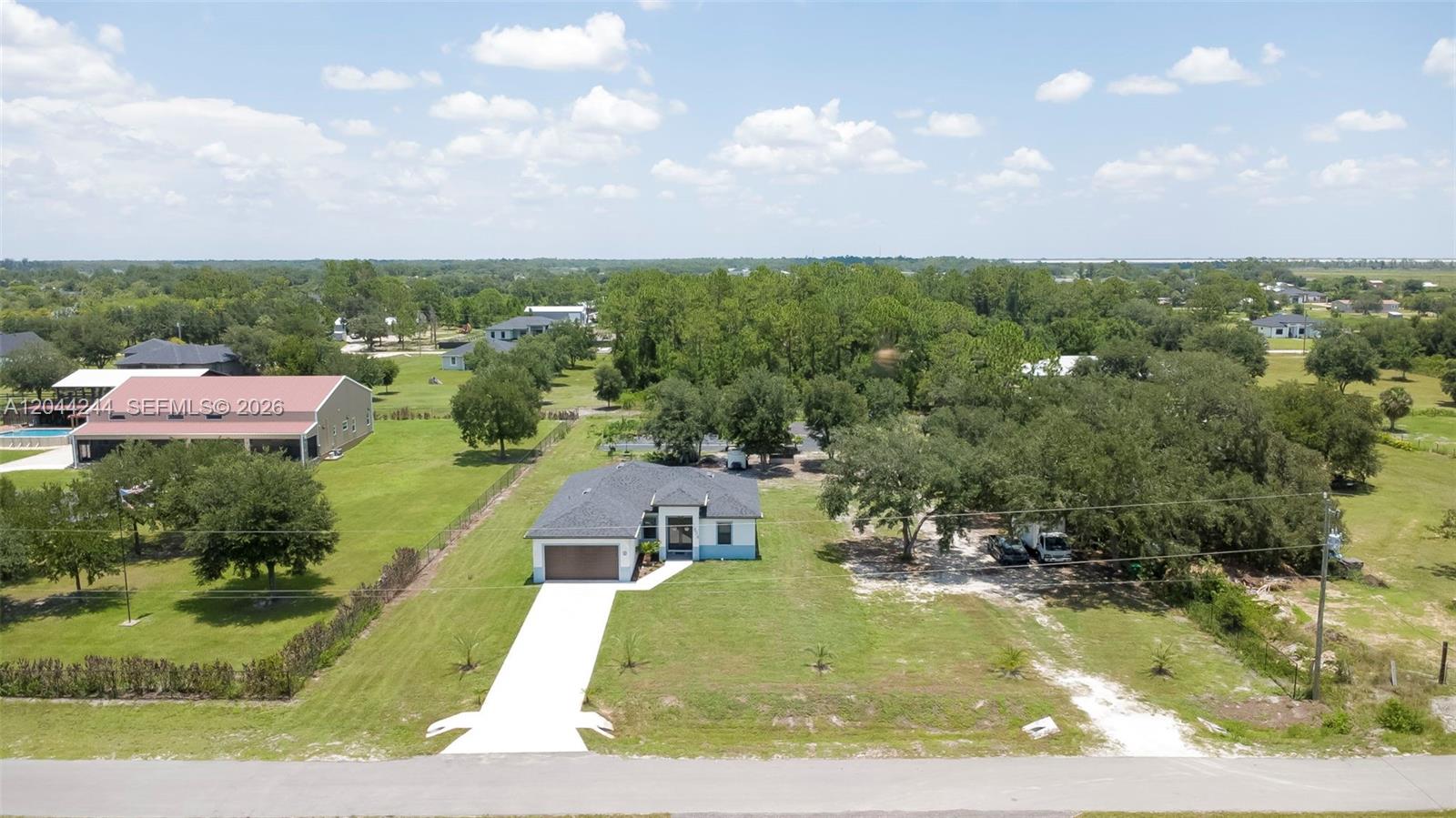 An aerial view shows a single-story house with a driveway and surrounding grassy yard — 7834 14TH PL, La Belle FL 33935, LA BELLE, FL