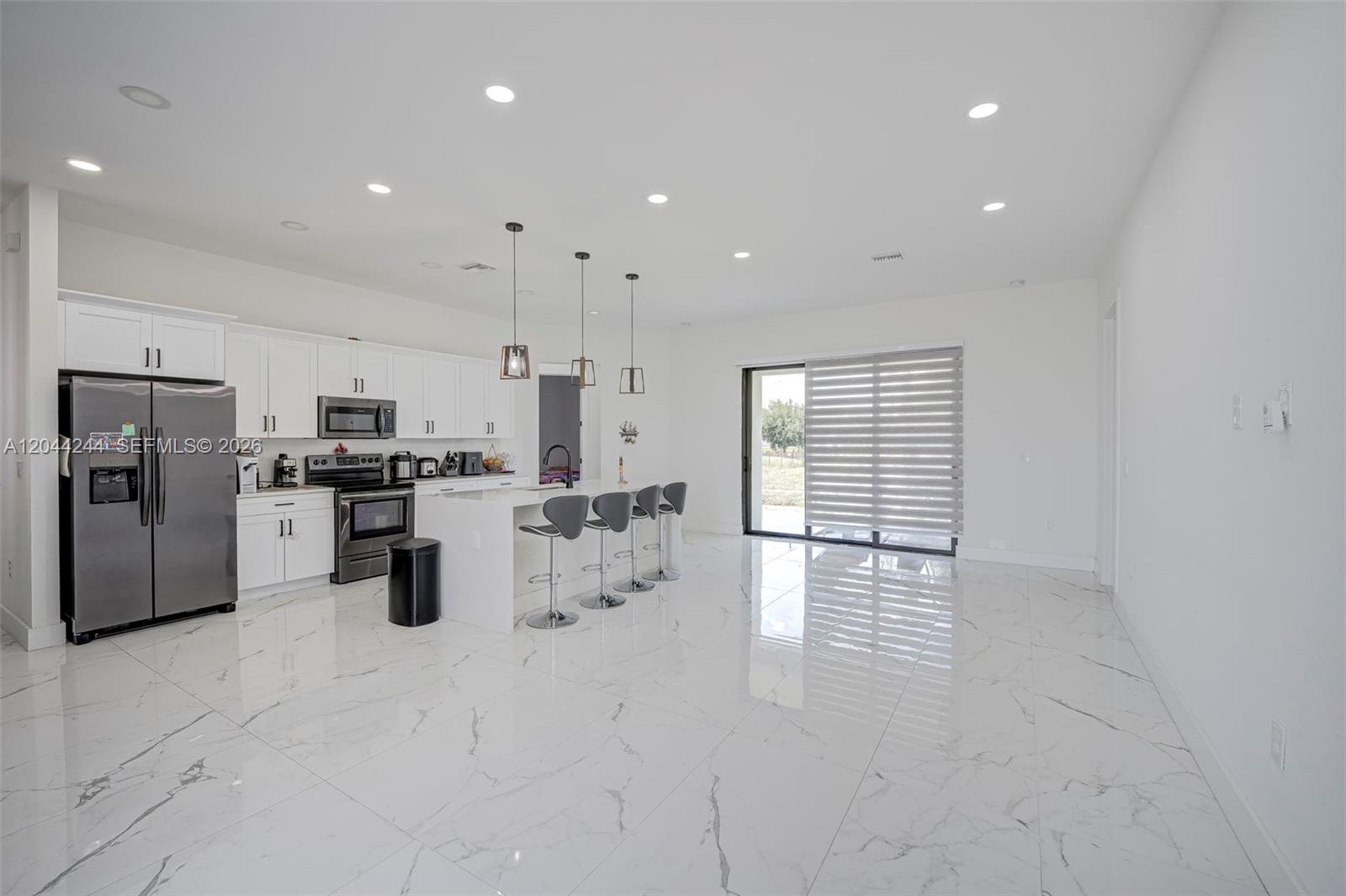 A modern kitchen with white cabinets, stainless steel appliances, and white marble-patterned tile flooring — 7834 14TH PL, La Belle FL 33935, LA BELLE, FL