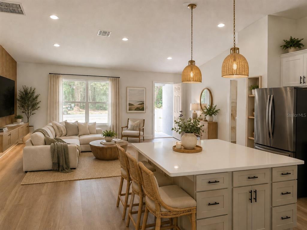 An open-concept living room and kitchen featuring a large island, sectional sofa, and wood flooring — 10048 N BLYER WAY, CITRUS SPRINGS, FL