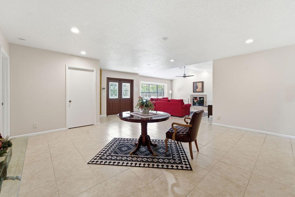 A spacious tiled foyer features a round pedestal table, a single chair, and a rug — 5562 Reynolds Road, Lake Worth FL 33449, LAKE WORTH, FL