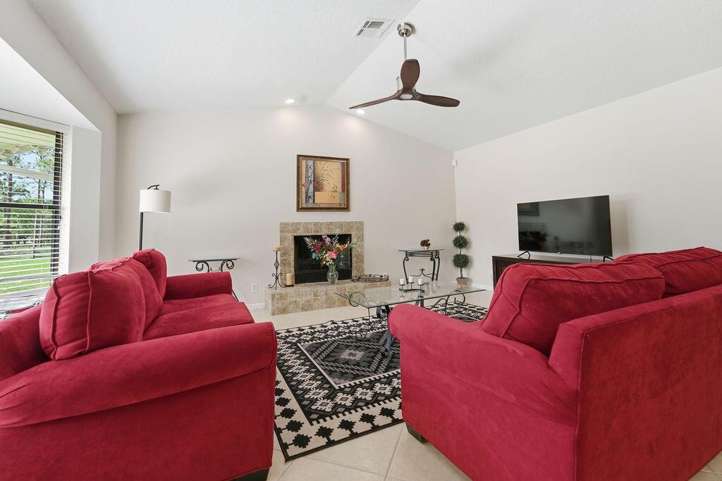 A living room features two red sofas, a fireplace, a ceiling fan, and a patterned rug — 5562 Reynolds Road, Lake Worth FL 33449, LAKE WORTH, FL