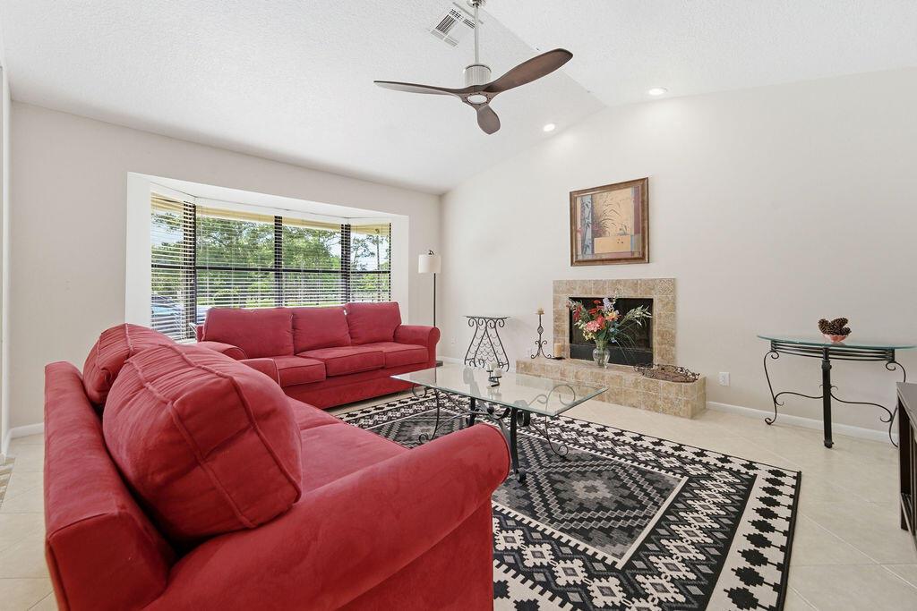 A living room features red sofas, a fireplace, a glass coffee table, and patterned rug — 5562 Reynolds Road, Lake Worth FL 33449, LAKE WORTH, FL