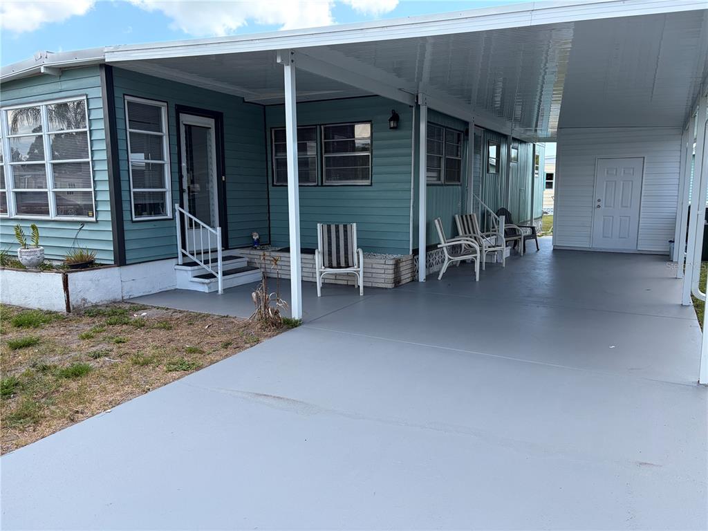 A teal mobile home features a covered carport, a concrete patio, and a front entrance — 5221 BEECHMONT AVENUE, SARASOTA, FL