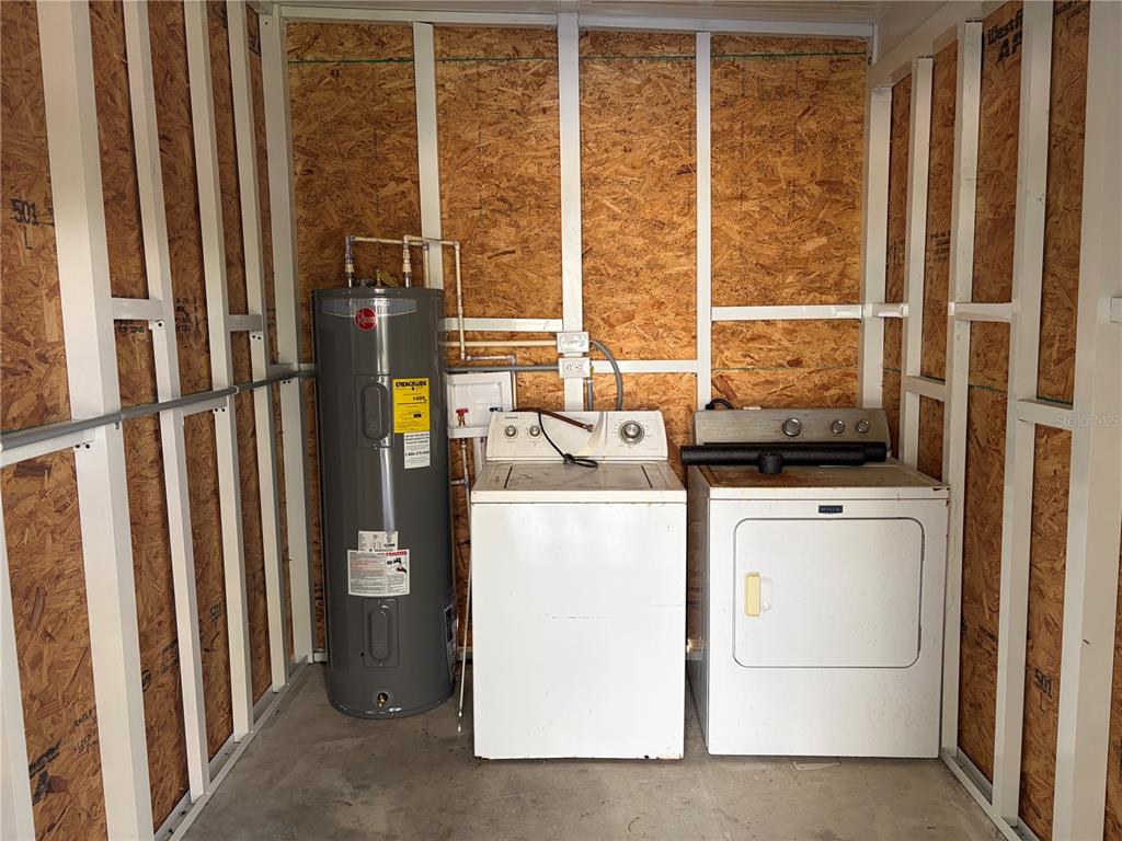 A utility room features an exposed wood-frame wall, a water heater, a washer, and a dryer — 5221 BEECHMONT AVENUE, SARASOTA, FL