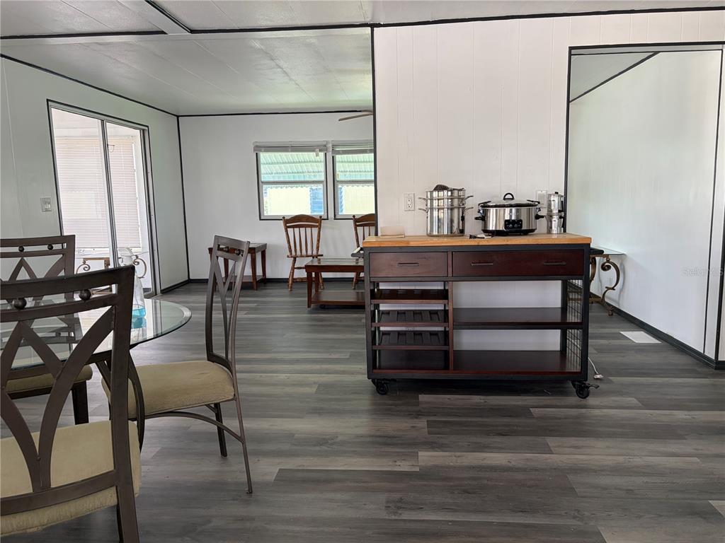 A dining area and kitchen island with wood-look flooring and white paneled walls — 5221 BEECHMONT AVENUE, SARASOTA, FL