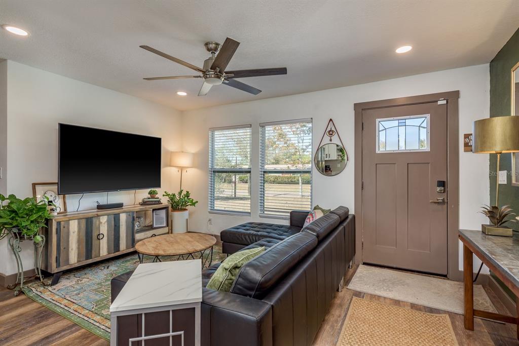 A living room features a dark leather sectional, a television console, and a front door — 4430 W TRILBY AVENUE, TAMPA, FL