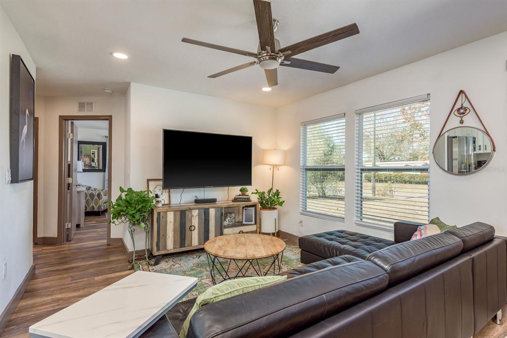 A living room features a dark leather sectional, a wood coffee table, and a television — 4430 W TRILBY AVENUE, TAMPA, FL
