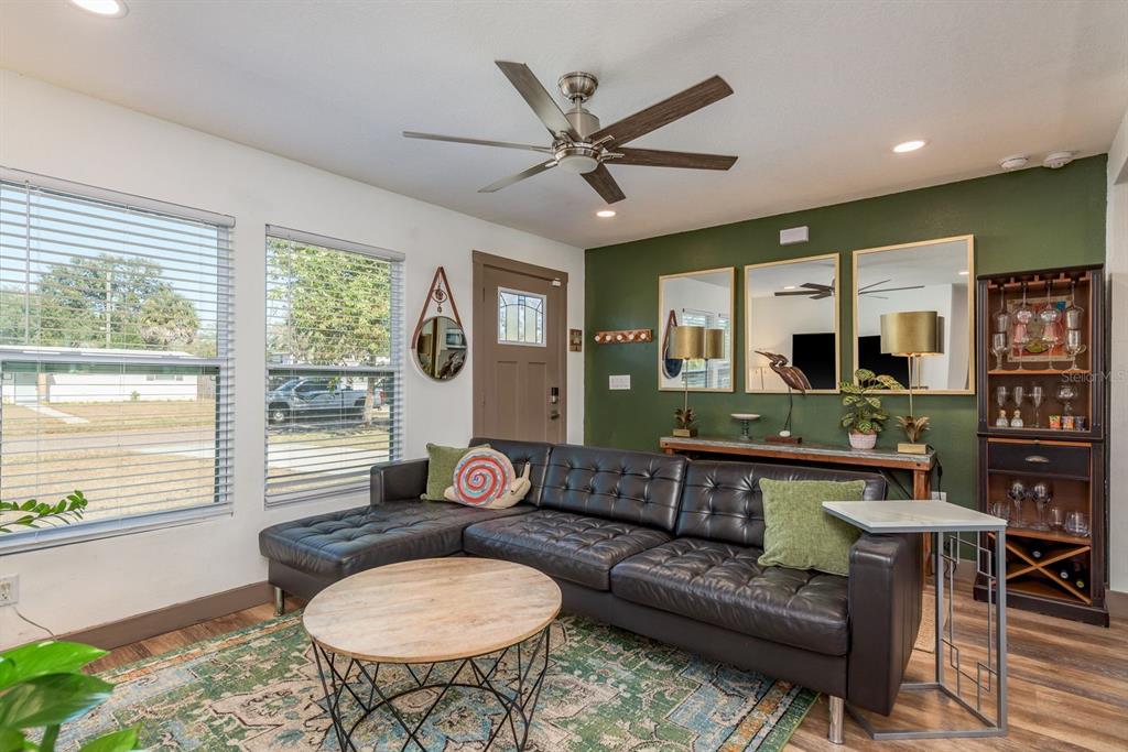 A living room features a dark leather sectional, a round coffee table, and green walls — 4430 W TRILBY AVENUE, TAMPA, FL