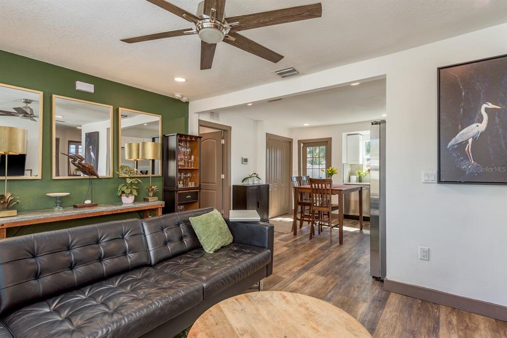 A living room with a black leather sofa, green accent wall, and adjacent dining area — 4430 W TRILBY AVENUE, TAMPA, FL