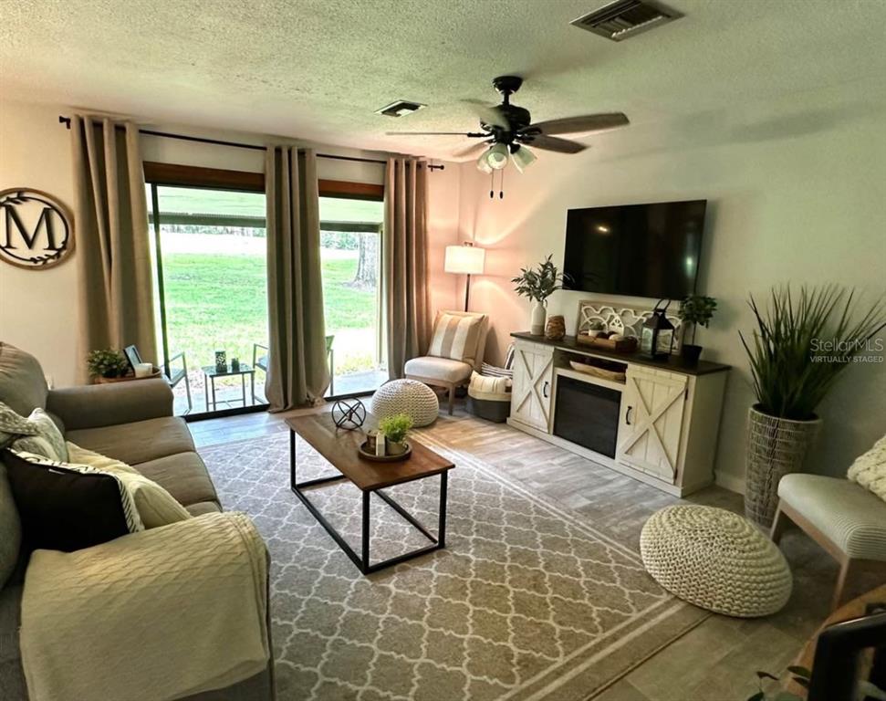 A living room features a sofa, coffee table, fireplace console, and sliding glass doors — 19660 SW 83RD PLACE ROAD UNIT C17, DUNNELLON, FL
