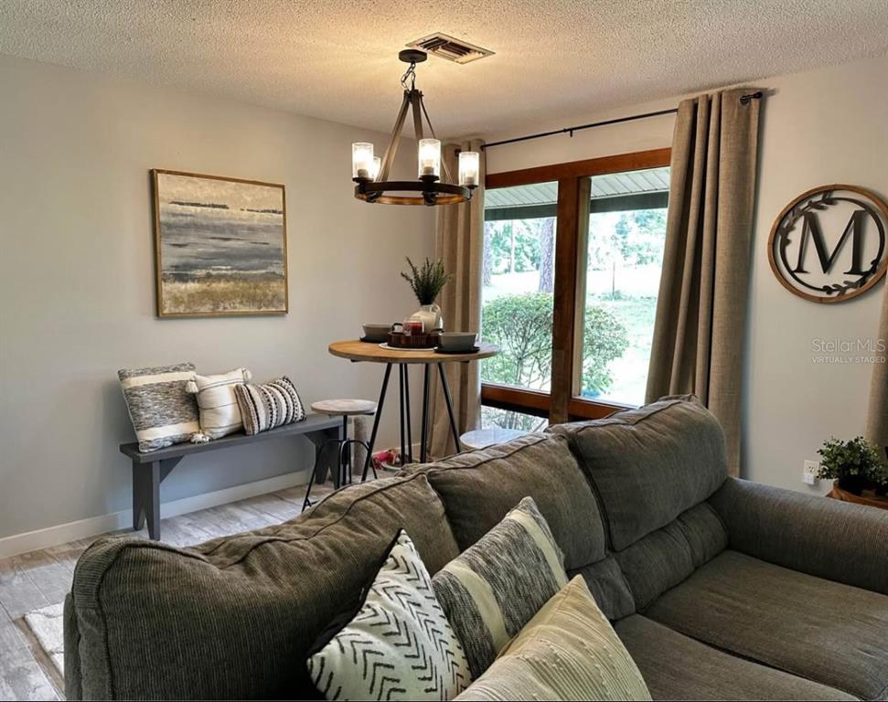A living room features a dining nook with a bench, round table, and chandelier — 19660 SW 83RD PLACE ROAD UNIT C17, DUNNELLON, FL