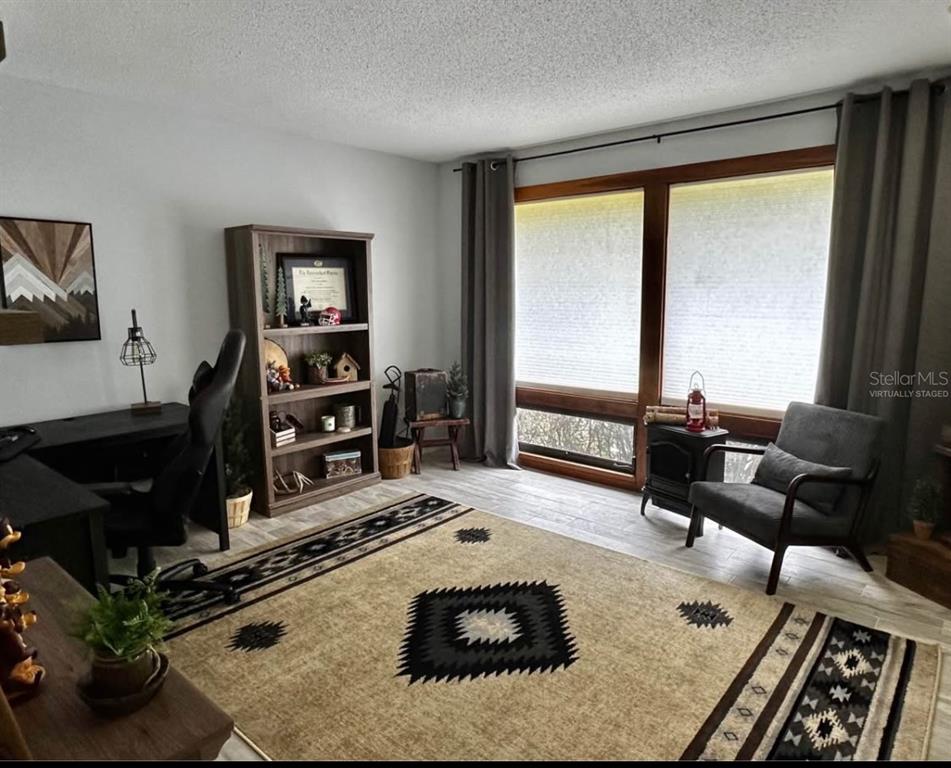 This home office features a desk, a bookshelf, a gray armchair, and a patterned area rug — 19660 SW 83RD PLACE ROAD UNIT C17, DUNNELLON, FL