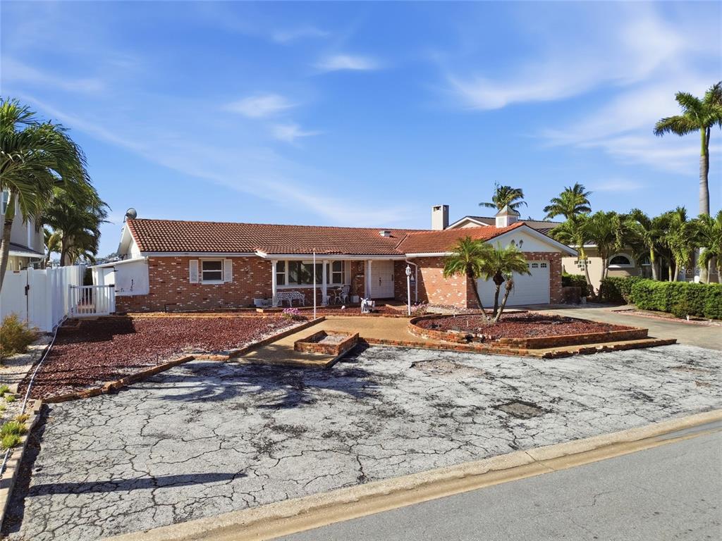 A single-story brick house with a tiled roof, a cracked driveway, and a front garden — 4 BELLEVUE DRIVE, TREASURE ISLAND, FL