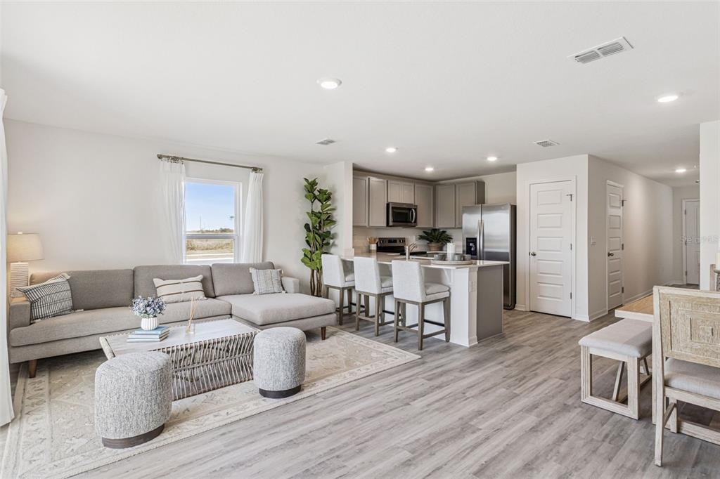 An open-concept living room and kitchen feature gray cabinetry, a kitchen island, and wood flooring — 4711 TONY STREET, LAKE WALES, FL