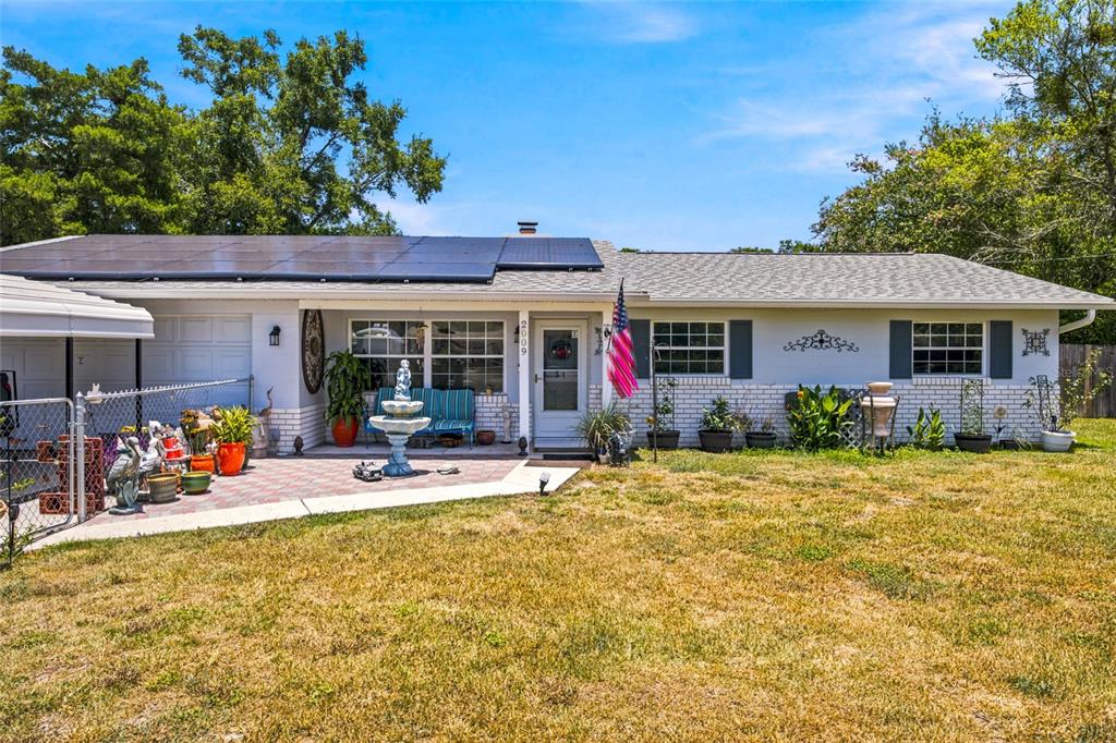 A single-story house with a brick facade, solar panels, and a front patio with a fountain — 2009 NE 49TH STREET, OCALA, FL