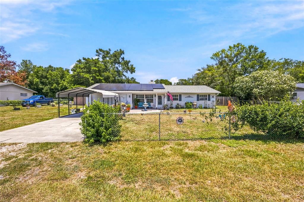 A single-story house with a carport, solar panels, and a chain-link fenced front yard — 2009 NE 49TH STREET, OCALA, FL