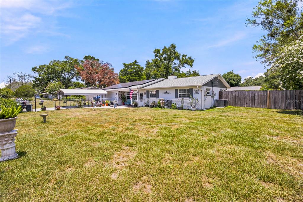 A single-story house with a white exterior, a covered patio, and a large grassy yard — 2009 NE 49TH STREET, OCALA, FL