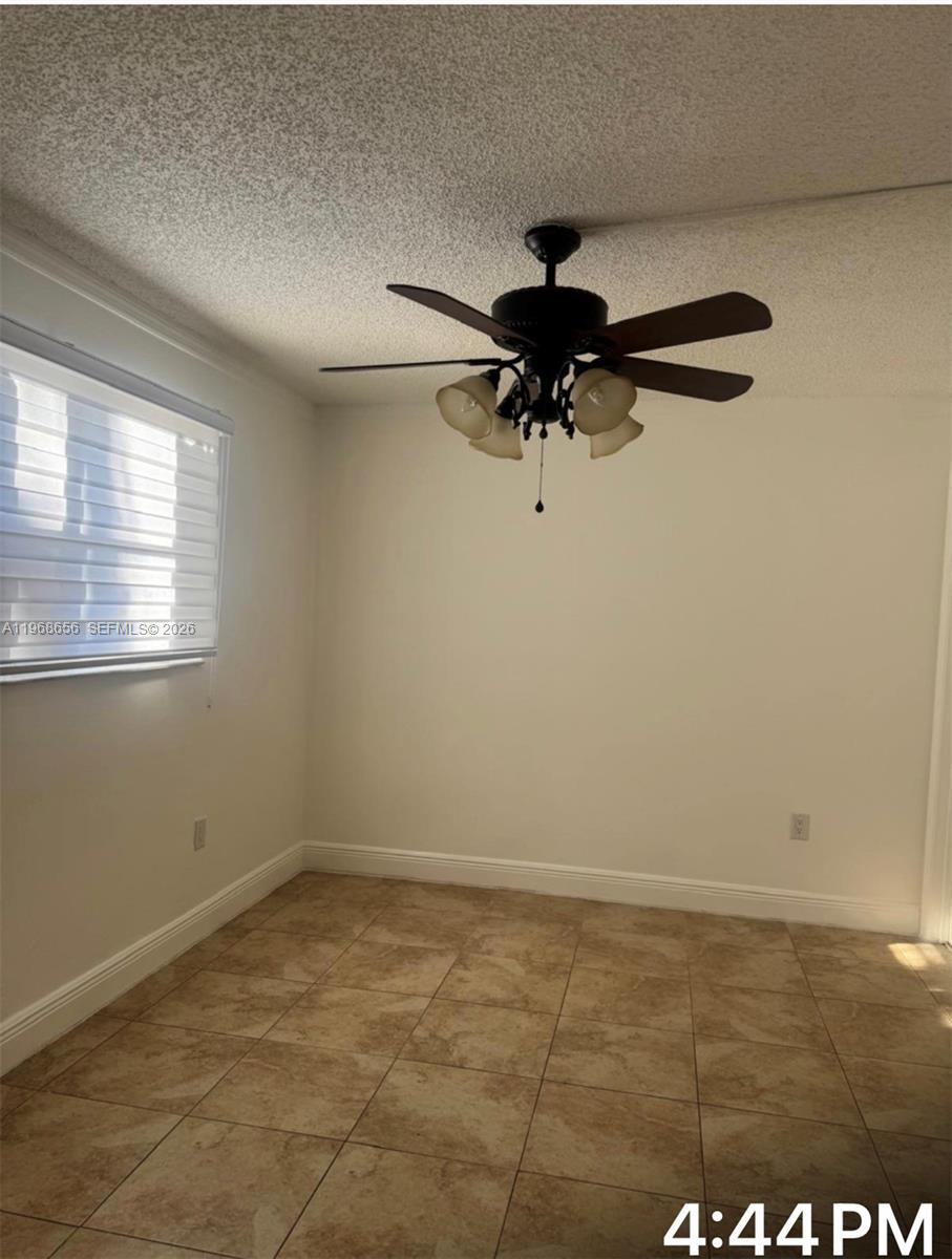 An empty room features tiled flooring, a ceiling fan with lights, and a window — 3110 N Pine Island Rd # 110, Sunrise FL 33351, SUNRISE, FL
