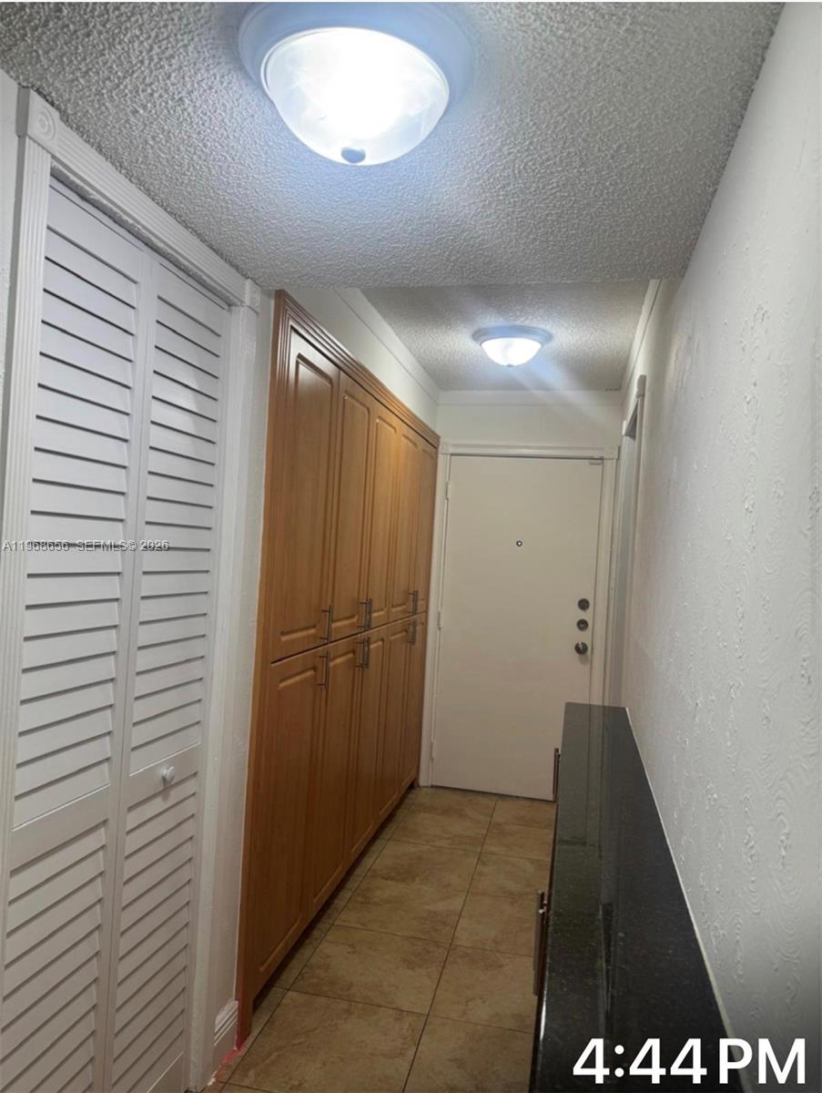 A narrow hallway features wood cabinetry, a white louvered closet door, and a black countertop — 3110 N Pine Island Rd # 110, Sunrise FL 33351, SUNRISE, FL