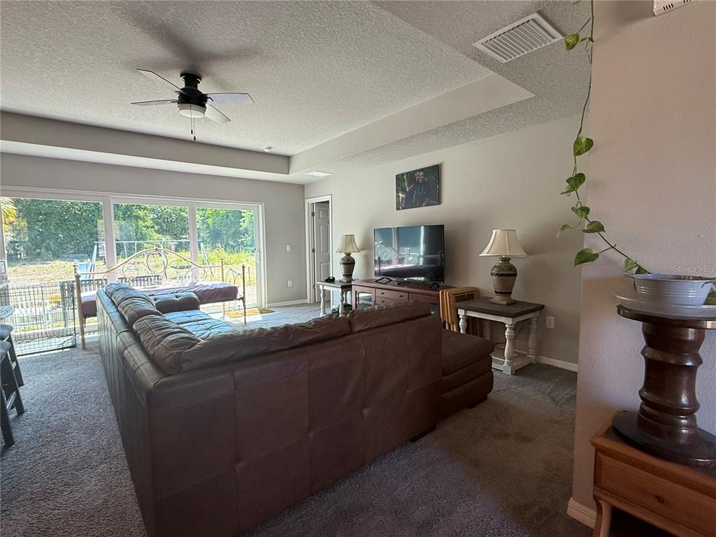 A living room features a large brown sectional sofa, a television, and sliding glass doors — 15808 ARCHER STREET, HUDSON, FL