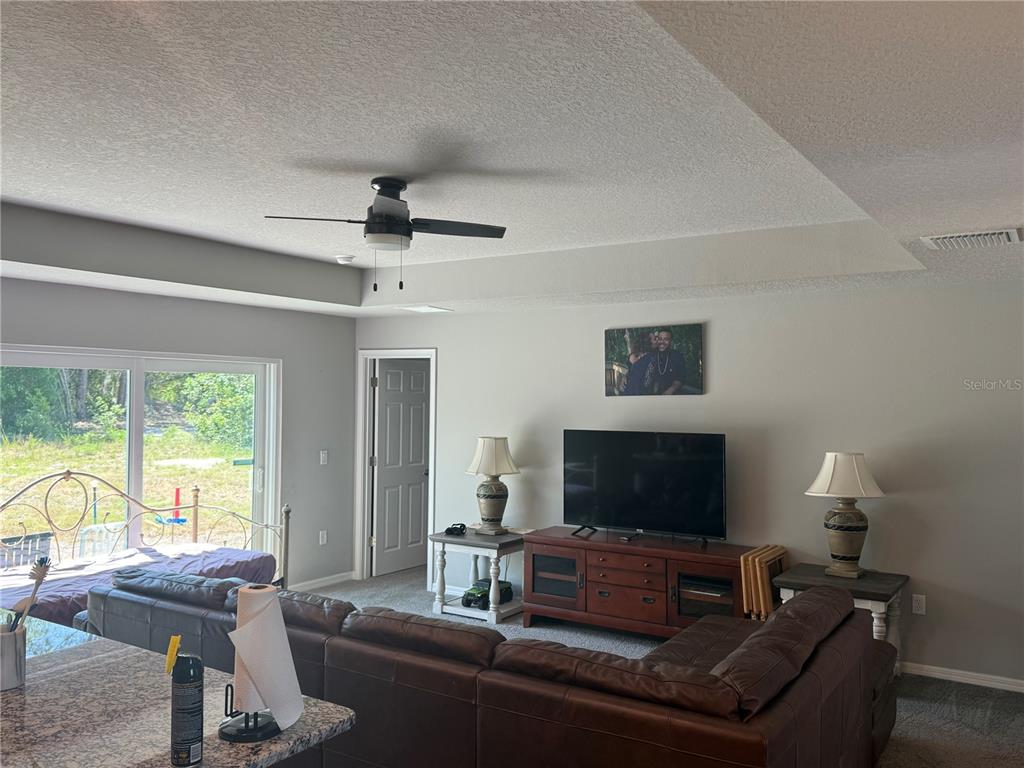 A living room features a brown sectional sofa, a television console, and a ceiling fan — 15808 ARCHER STREET, HUDSON, FL
