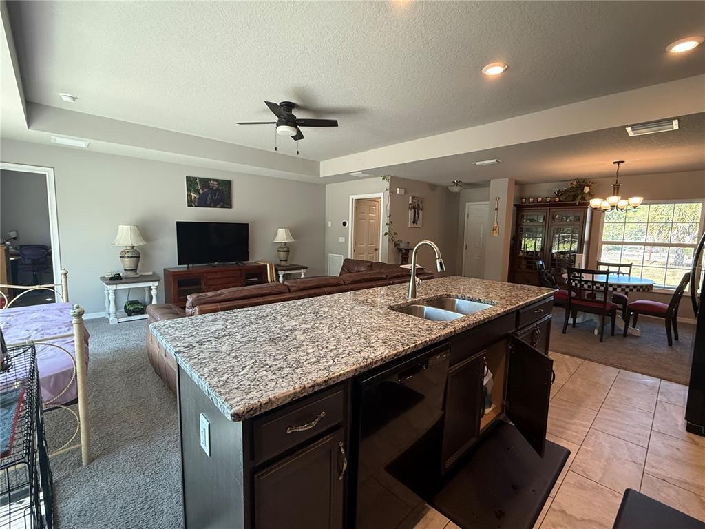 A kitchen island with granite countertops sits in front of an open-concept living area — 15808 ARCHER STREET, HUDSON, FL
