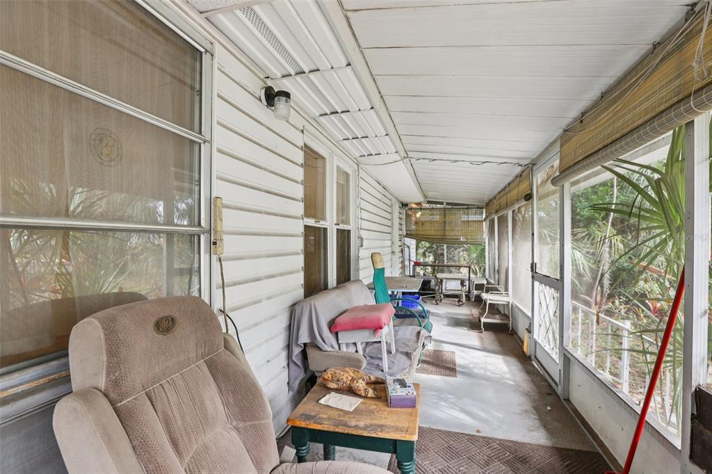 A screened-in porch with white siding, concrete flooring, and various pieces of casual furniture — 38025 13TH AVENUE, ZEPHYRHILLS, FL