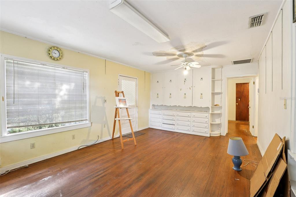 A room with hardwood floors, a ceiling fan, built-in white cabinetry, and a large window — 38025 13TH AVENUE, ZEPHYRHILLS, FL