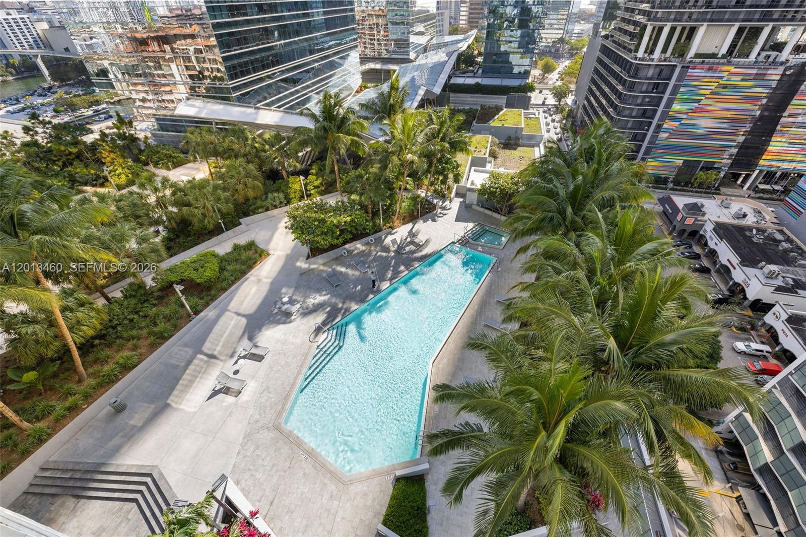 An elevated view of a swimming pool surrounded by palm trees and modern high-rise buildings — 88 SW 7th St # 1201, Miami FL 33130, MIAMI, FL