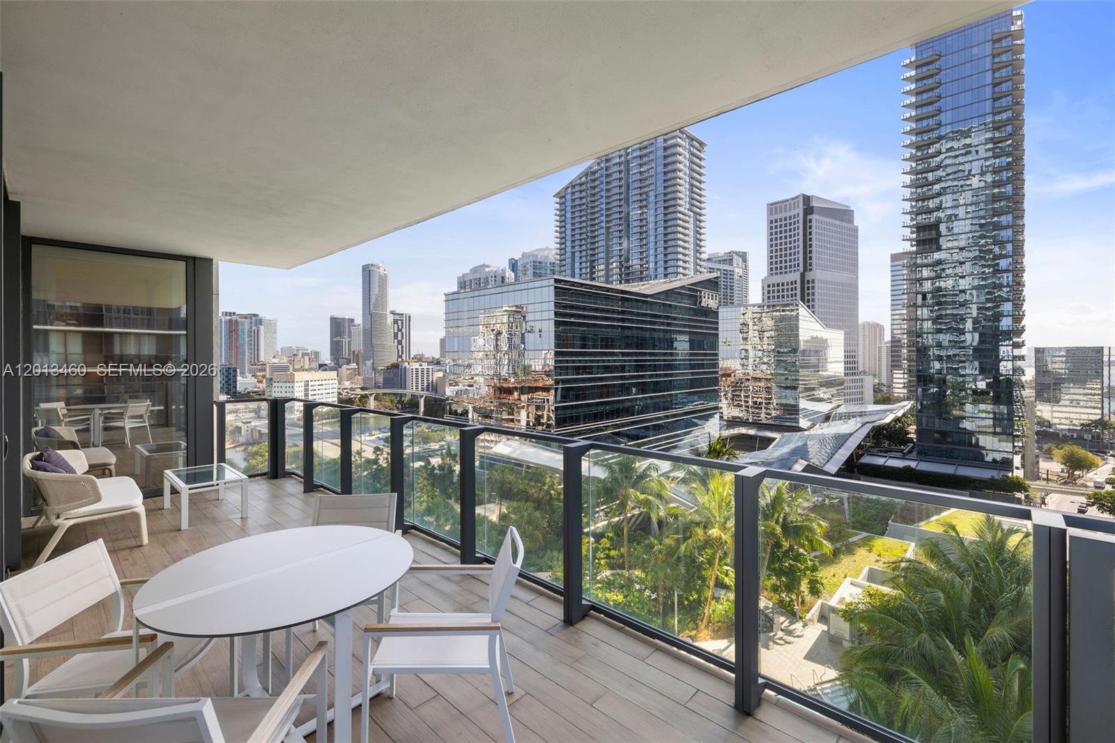 A high-rise balcony features outdoor furniture, glass railings, and a view of city skyscrapers — 88 SW 7th St # 1201, Miami FL 33130, MIAMI, FL