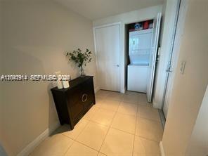 A small entryway with tile flooring, a dark wooden cabinet, and a stacked laundry unit — 7280 SW 90th St # 506, Miami FL 33156, MIAMI, FL